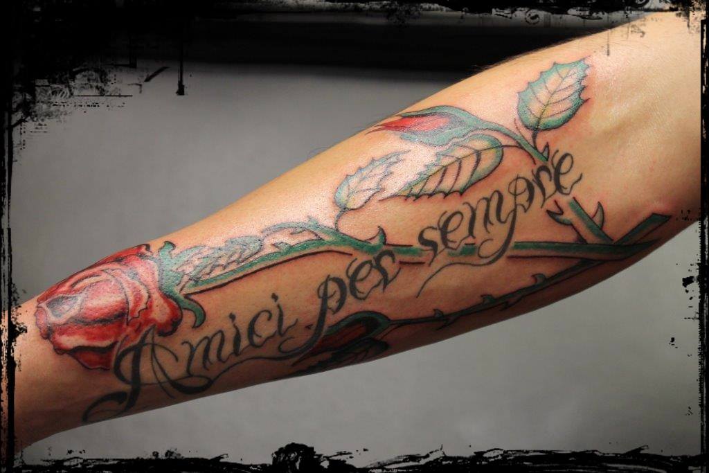 Schriftzug mit roten Rosen auf dem Unterarm. 